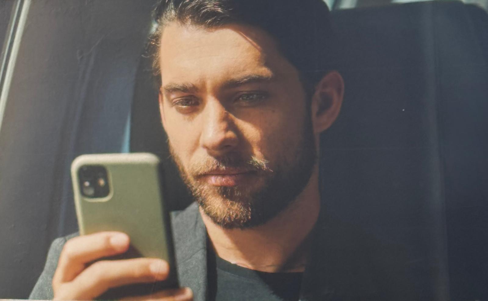 Person sitzt nachdenklich mit Smartphone in der Hand